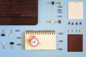 On a blue background neatly spread out clerical clips and clothespins. In the corner is a black...