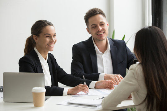 Friendly business team members chatting laughing together during office break, happy coworkers talking having good relations and pleasant conversation at work, smiling hr interviewing job applicant