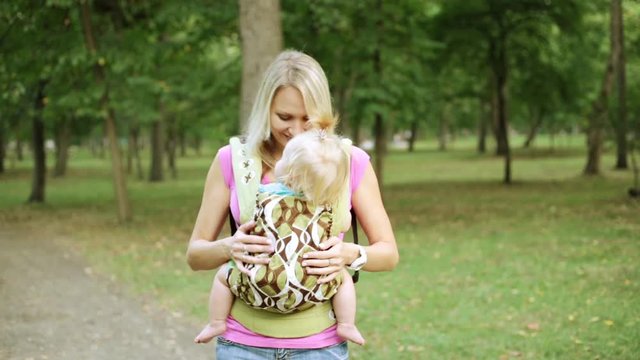 A woman with a baby in an ergo backpack.
