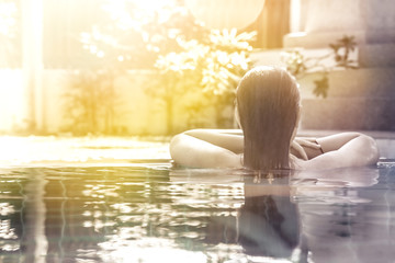 woman relaxing in hotel  spa swimming pool looking at view with sunlight and copy space - obrazy, fototapety, plakaty