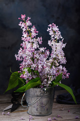 Rustic still life. Bouquet of lilac in a bucket on a wooden table