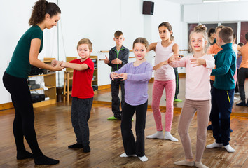 positive boys and girls rehearsing ballet dance in studio