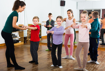Obraz premium positive boys and girls rehearsing ballet dance in studio
