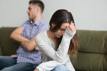 Depressed frustrated millennial woman feeling offended and sad after fight with stubborn selfish husband sitting on couch, unhappy young wife tired of bad relationships, upset about marriage problems