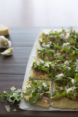 Homemade flatbread pizza with garlic, parmesean, arugula, and prosciutto 