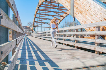 Jogging. Beautiful woman is running across the bridge.