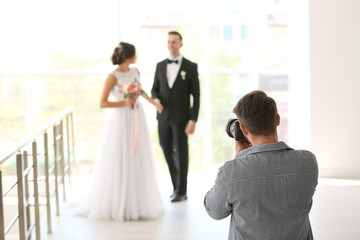 Professional photographer taking photo of wedding couple in studio