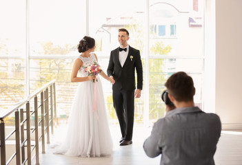 Professional photographer taking photo of wedding couple in studio