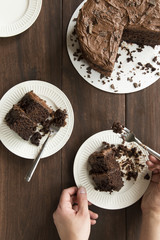 Chocolate cake with hands and utensils shown