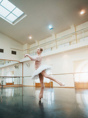 Young attractive blonde woman in white tutu clothing practicing in classical ballet in the gym. Minimalism interior, dancing sensual dance. © kohanova1991