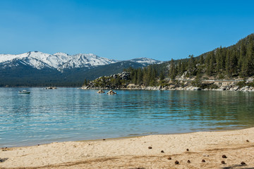 Lake Tahoe in Nevada with trees and snowcapped mountains in background.