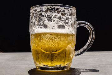 Frosty and refreshing beer mug already in half of its capacity to black background