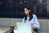 Young businesswoman working on laptop while having coffee