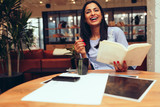 Smiling businesswoman holding book while sitting in office