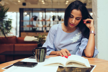 Businesswoman reading a book while sitting in office