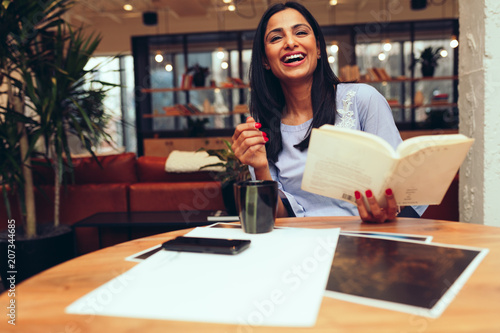 Smiling businesswoman holding book while sitting in office