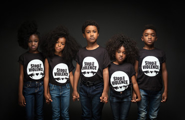 Portrait of children standing against black background