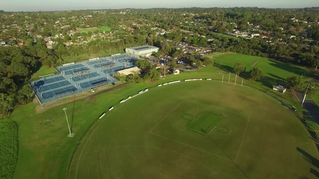 Slow aerial descend over sports oval and netball courts in Australia