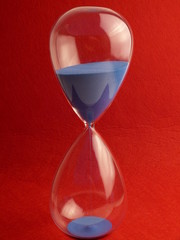 hourglass framed in the center running blue sand under red felt paper background