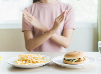 Obraz na płótnie Canvas Woman on dieting for good health concept. Woman doing cross arms sign to refuse junk food or fast food (hamburger and potato fried) that have many fat.