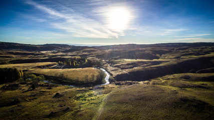 Vista aérea de un valle con río y pinares en medio de las sierras, hermosa vista del atardecer.