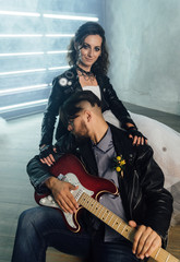 Wedding in the style of rock. Rocker or Biker wedding. Guys with stylish leather jackets. It's a rock'n'roll baby Sweet couple in a photo studio. Steep shooting with electric guitar and smoke.