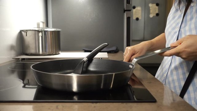 Female hand placed Teflon pan on electric stove for cooking