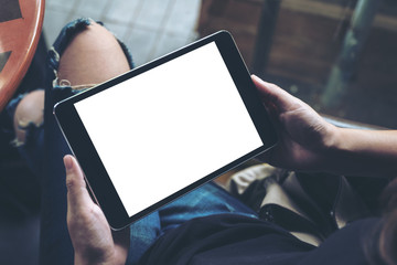 Mockup image of a woman sitting cross legged and holding black tablet pc with blank white desktop screen