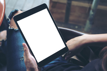 Mockup image of a woman sitting cross legged and holding black tablet pc with blank white desktop screen