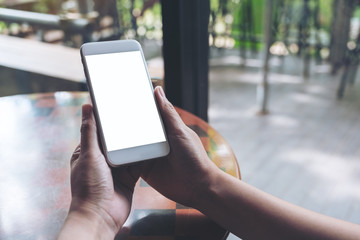 Mockup image of hands holding white mobile phone with blank desktop screen
