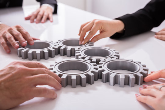 Businesspeople Joining Gears On Desk
