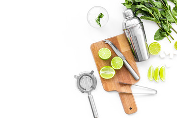 Make mojito cocktail with lime and mint. Shaker, strainer, glass near slices of lime on cutting board on white background top view copy space