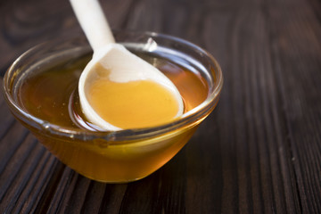 Honey dripping from honey dipper on yellow background. Thick honey dipping from the wooden honey...