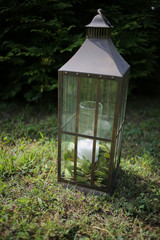 Wedding Decor Iron Lantern on Grass with a White Candle and Greenery Inside