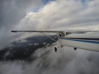 Airplane flying over the beautiful Canadian Mountain Landscape during a cloudy evening. Taken North of Vancouver, British Columbia, Canada.