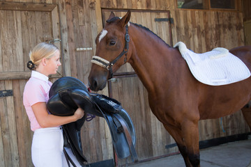 Young Woman Preparing to Saddle the Horse