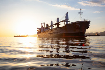 Fototapeta premium Old rusty ship is parked in the Port during a vibrant sunset. Taken in Vancouver, British Columbia, Canada.