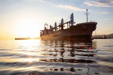 Old rusty ship is parked in the Port during a vibrant sunset. Taken in Vancouver, British Columbia,...