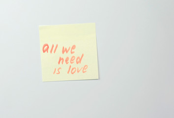 Note on yellow sticker paper sheets with motivation words all we need is love.