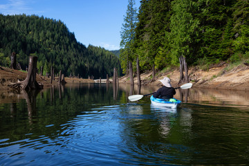 Fototapeta na wymiar Kayaking during a vibrant morning surrounded by the Canadian Mountain Landscape. Taken in Stave Lake, East of Vancouver, British Columbia, Canada. Concept: Adventure, vacation, holiday