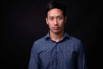 Obraz premium Young handsome Asian businessman against black background
