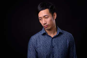 Obraz premium Young handsome Asian businessman against black background