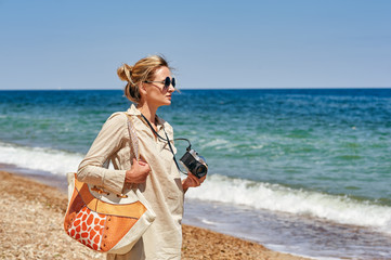 A young woman on a walk by the sea with an old camera