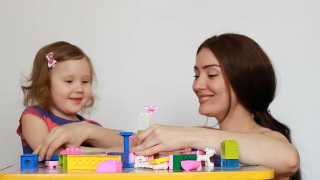 Mother and girl child busy building a constructor.