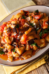 Warm salad from aubergines, tomatoes and garlic close-up. vertical