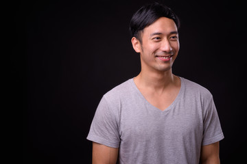 Young handsome Asian man against black background