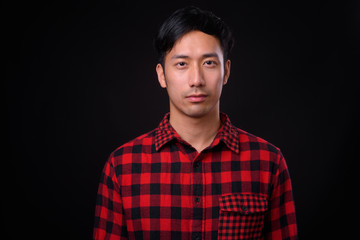 Young handsome Asian man against black background