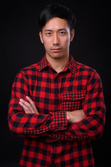 Young handsome Asian man against black background