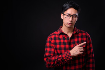 Young handsome Asian man against black background