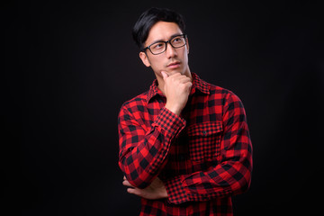 Young handsome Asian man against black background